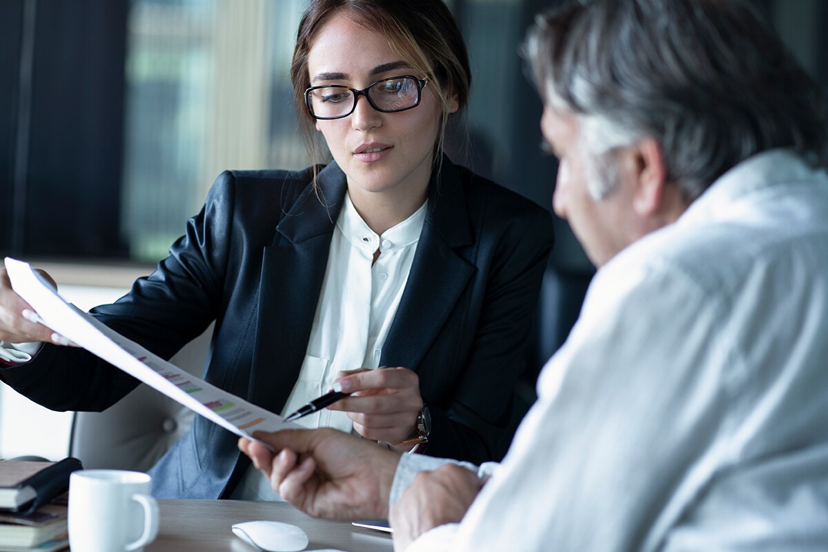 Woman pointing at document with a pen facing a man
